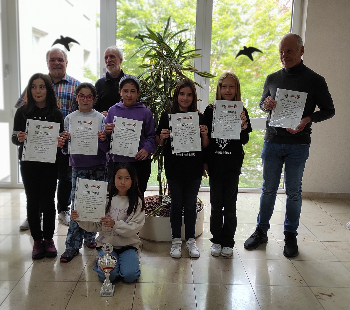 Schach-AG Grundschule Bitburg-Süd: Deutsches Meisterinnen-Team Schulschach WK G-M Hinten; SBRP-Präsident Achim Schmitt, 1. Vorsitzender SJRP Ludwig Peetz; Mitte: Zehra Betül Kara, Hayrunnisa Kara, Ipek Rana Kara, Dimitra Champeridou, Maria Cucorada , Trainer Paul Ewen,   Vorne: Silja Liu; es fehlt: Stella Liu						Foto: Mara Schlich